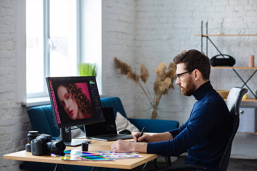 DotClick: A graphic designer working intently on a computer screen with design software, showcasing creative work.